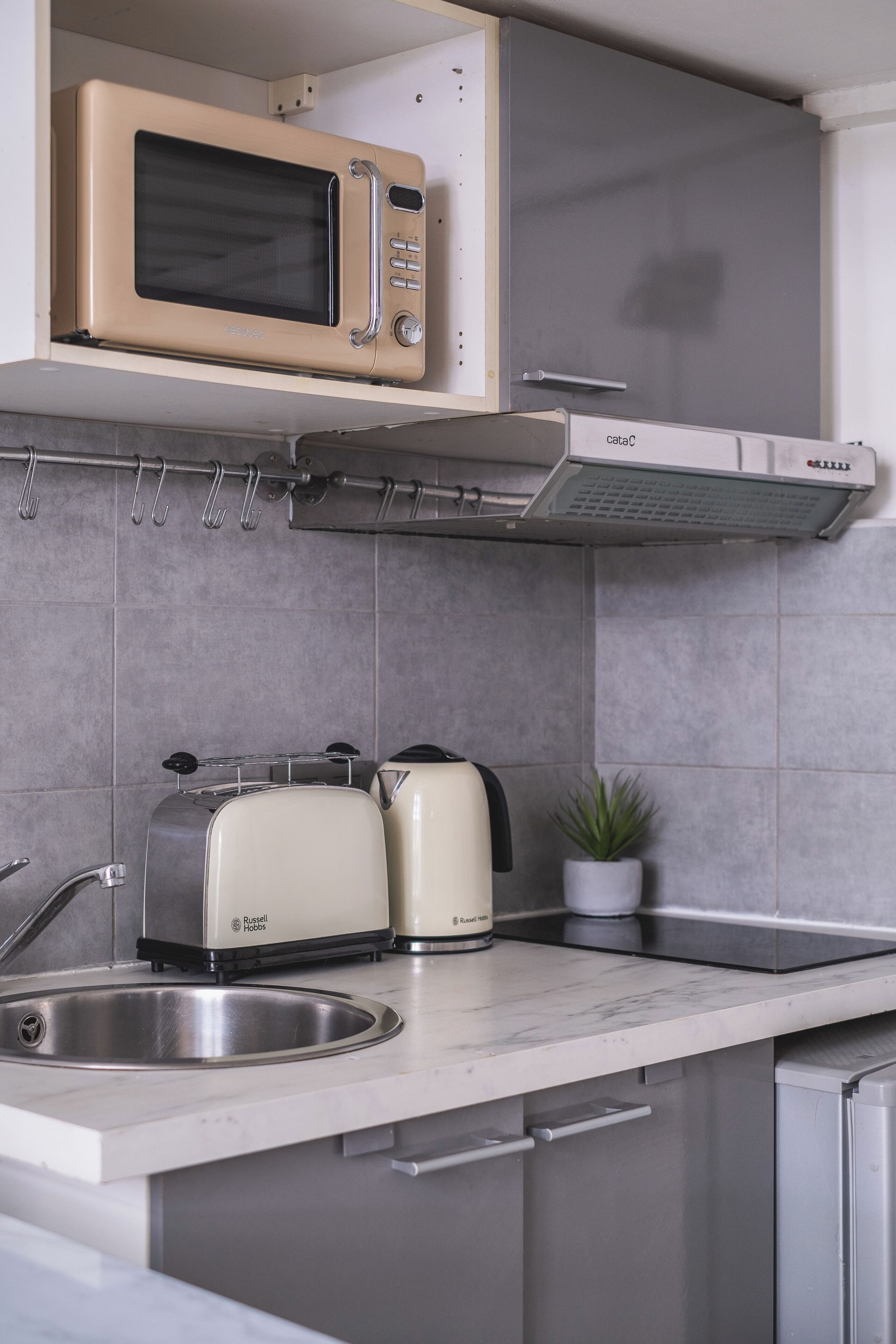 Een keuken met een magnetron, broodrooster en spoelbak.