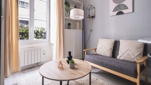 A modern living room with a sofa, a round coffee table, and a bookshelf. - Charmant studio au cœur du 16 (Paris)