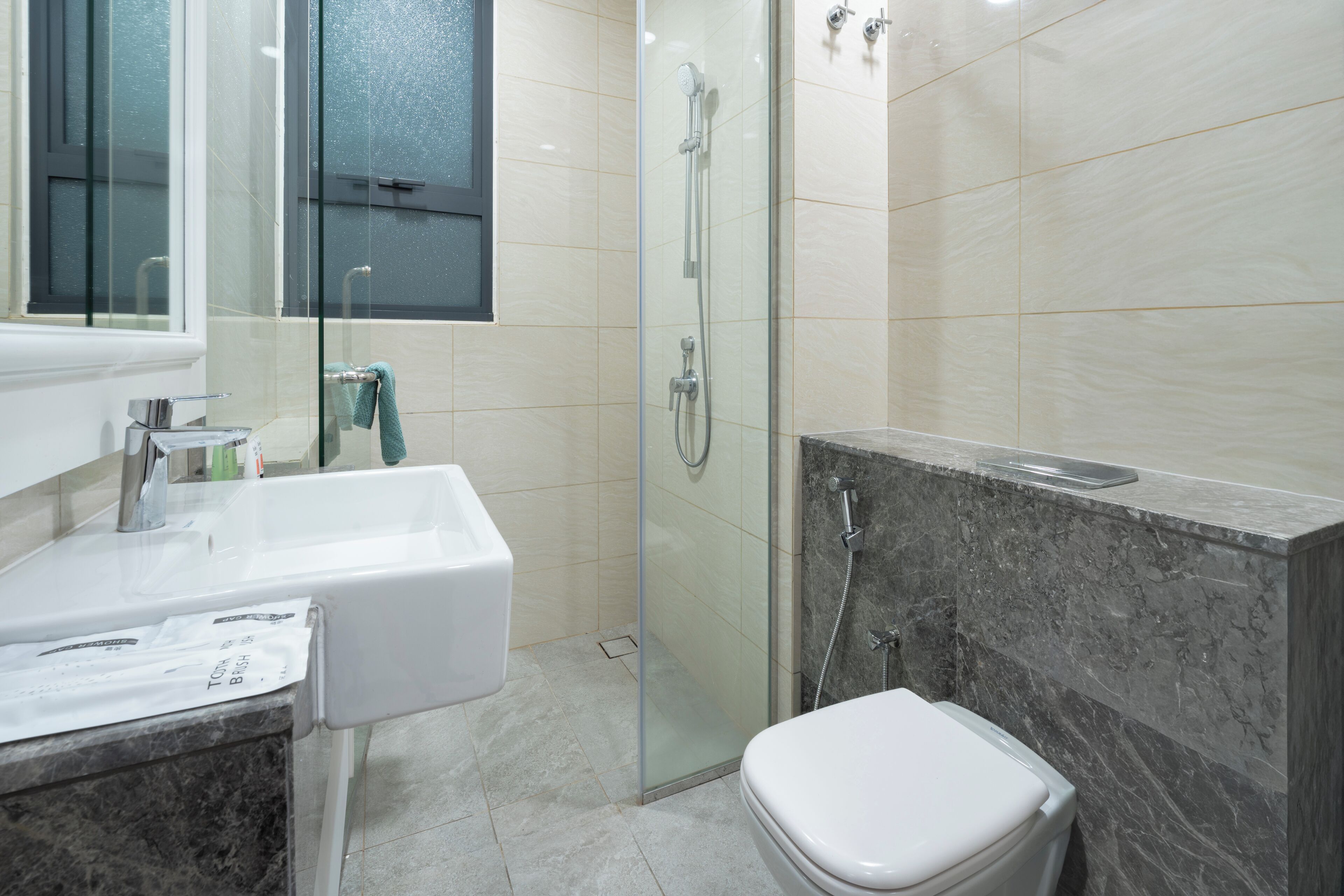 A modern bathroom with a glass-enclosed shower, a white sink, and a marble countertop.