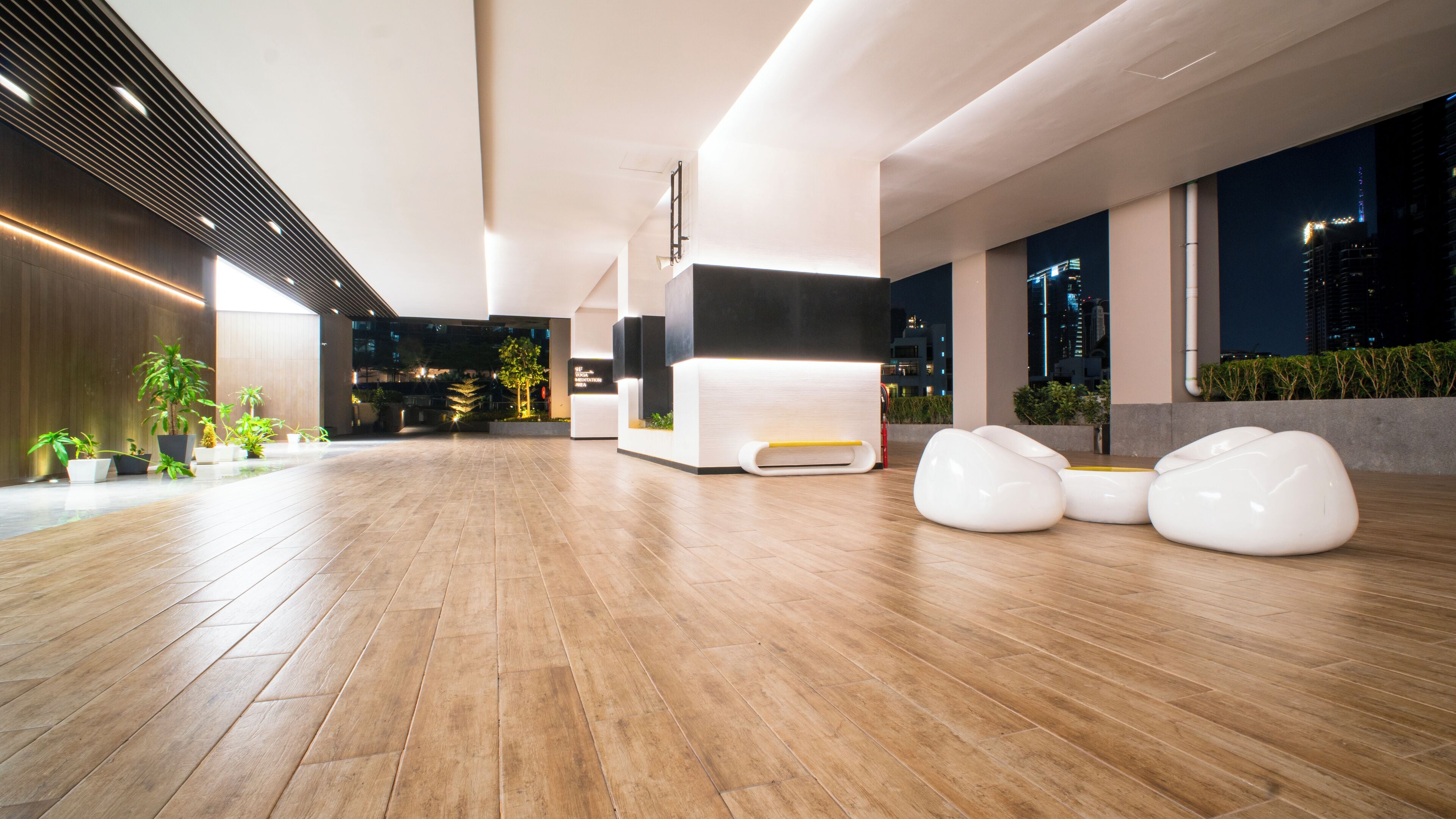 A spacious lobby with wooden flooring, modern seating, and large windows offering city views.