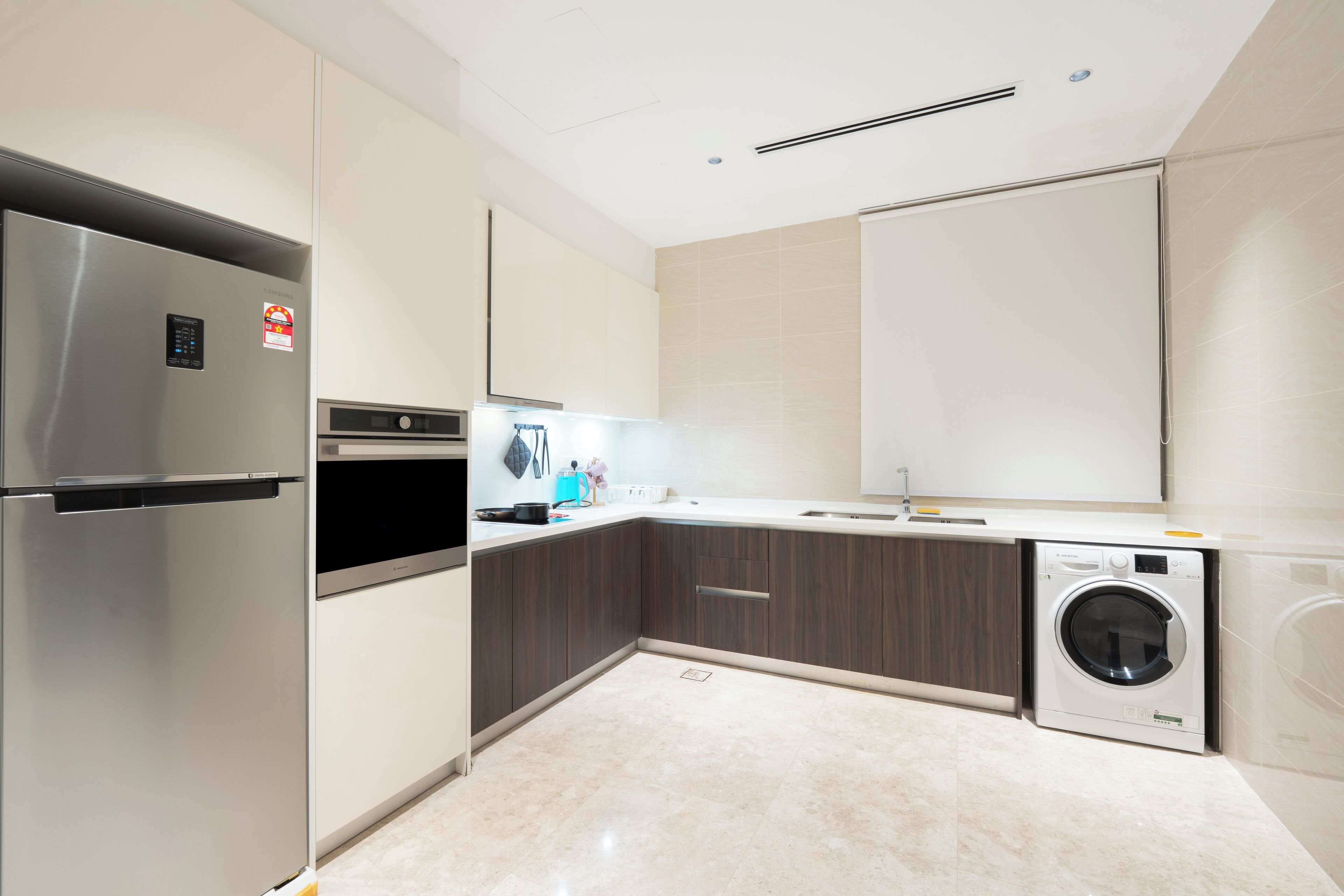 A modern kitchen with a stainless steel refrigerator, built-in oven, microwave, and a washing machine.