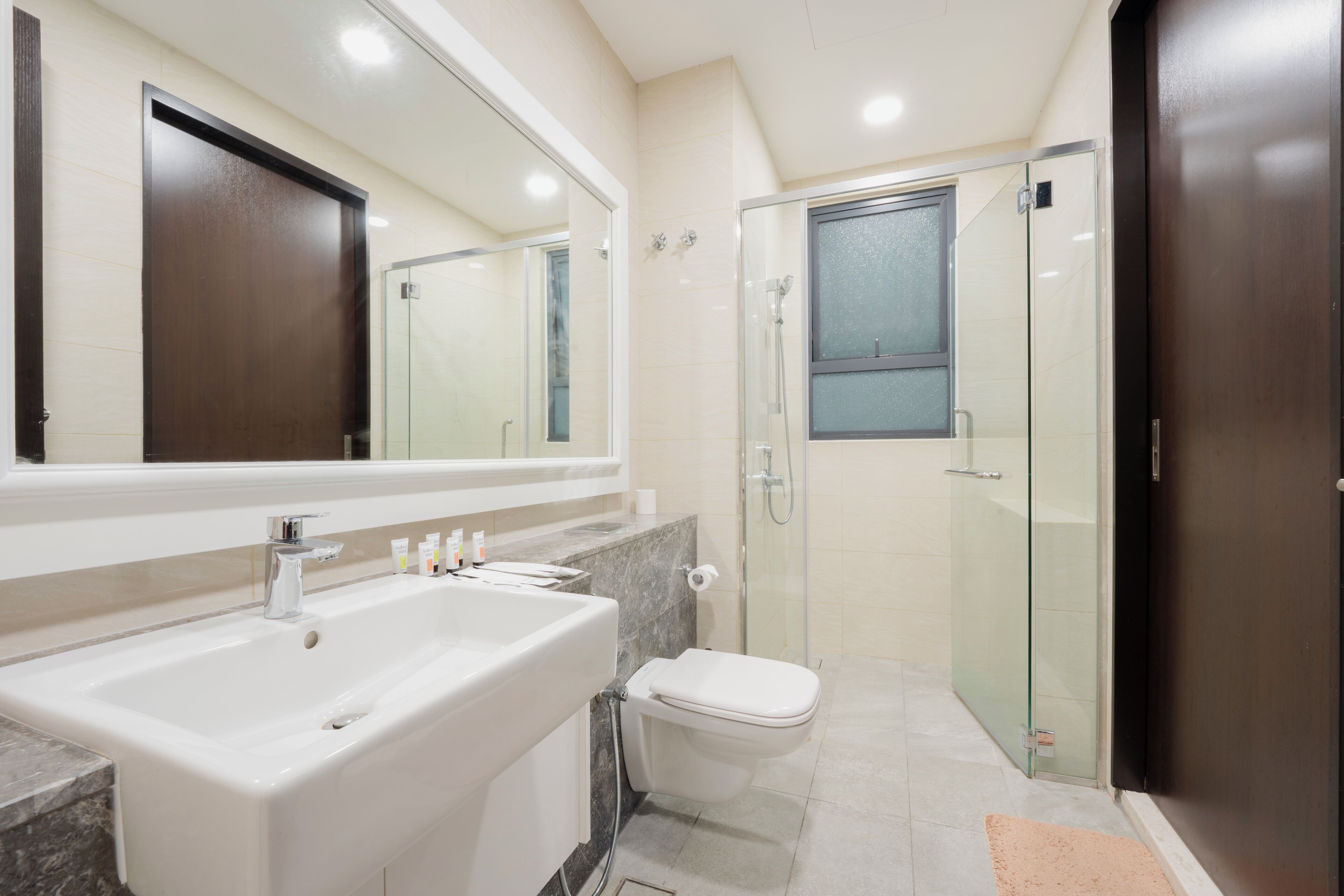 Une salle de bain moderne avec un grand lavabo, un miroir, des toilettes et une douche à parois de verre.