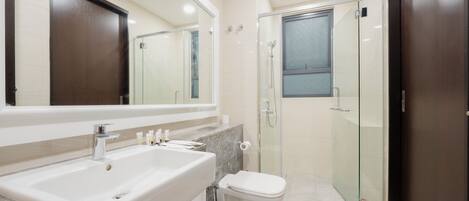 Une salle de bain moderne avec un grand lavabo, un miroir, des toilettes et une douche à parois de verre.