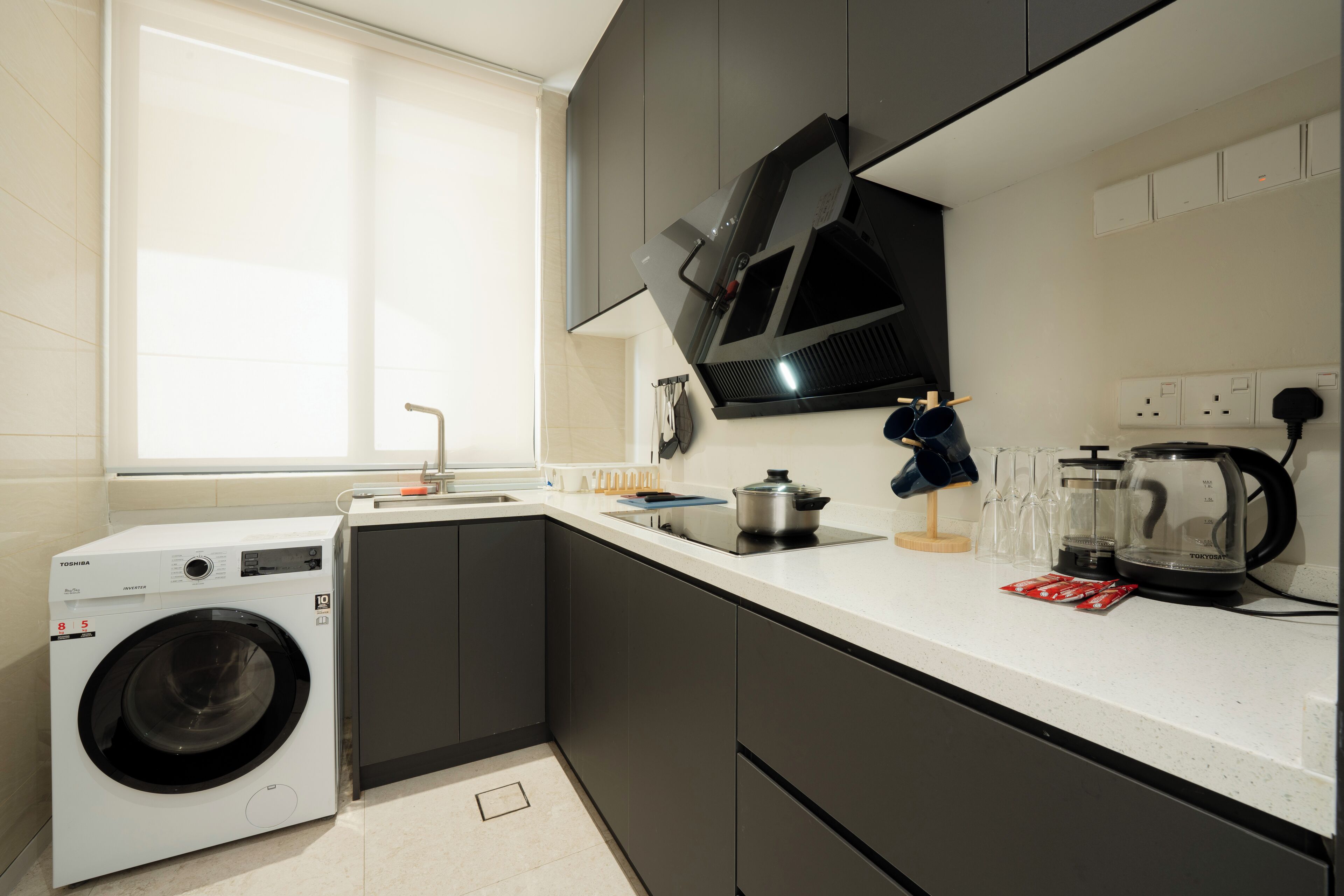 A compact kitchen with a washing machine, a microwave, and a coffee maker.