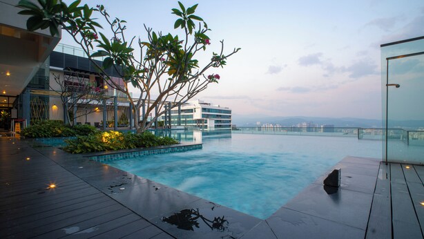Une piscine à débordement située sur le toit, offrant une vue imprenable sur les gratte-ciel de la ville, et entourée d’une végétation luxuriante et d’une architecture moderne.