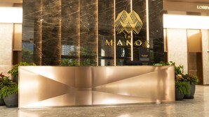 Un comptoir d’accueil doté d’une façade en marbre, d’un logo et d’une enseigne indiquant : « The Manor ».