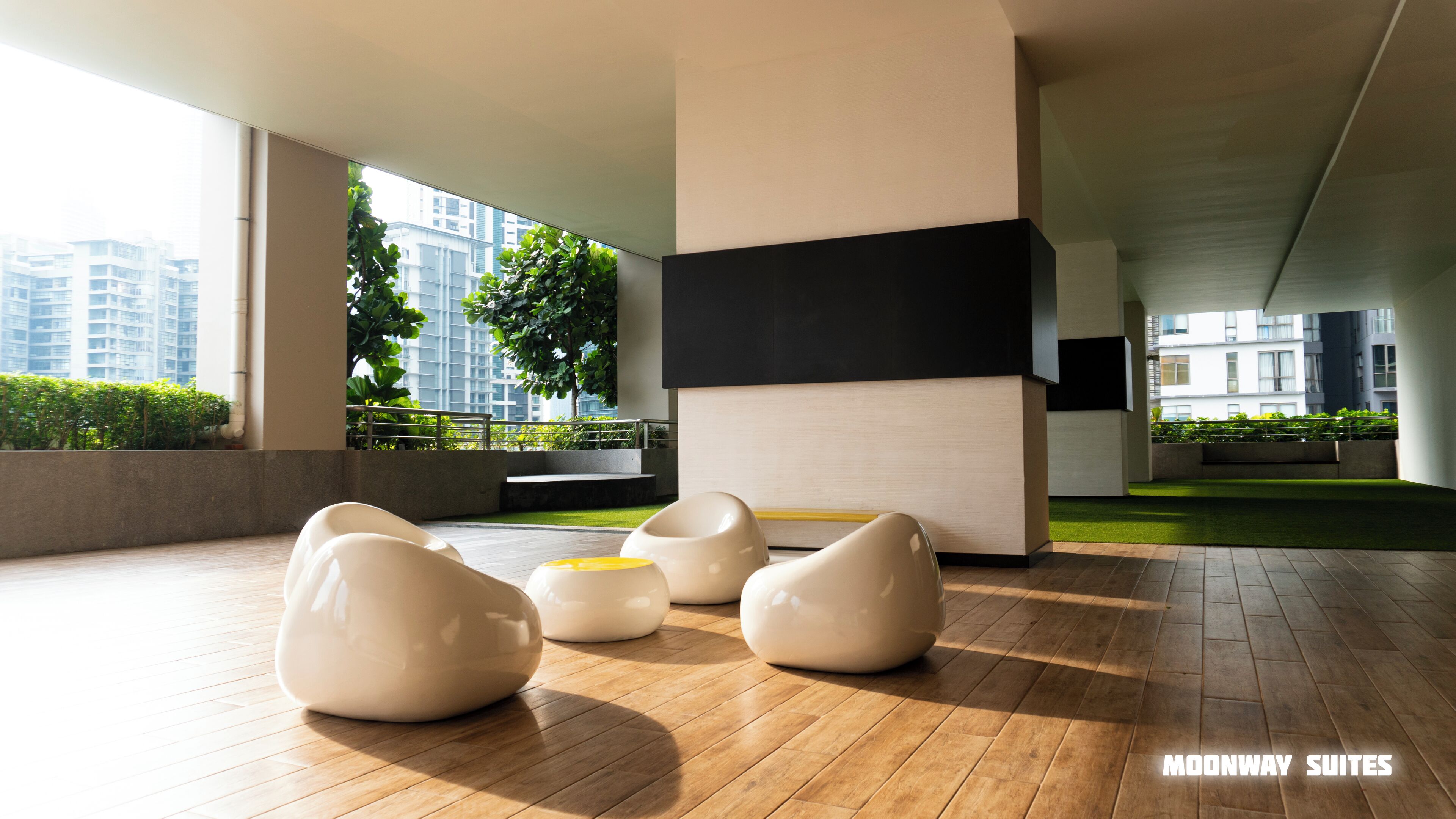 A modern interior with a wooden floor, white and black seating, and a view of buildings through large windows.