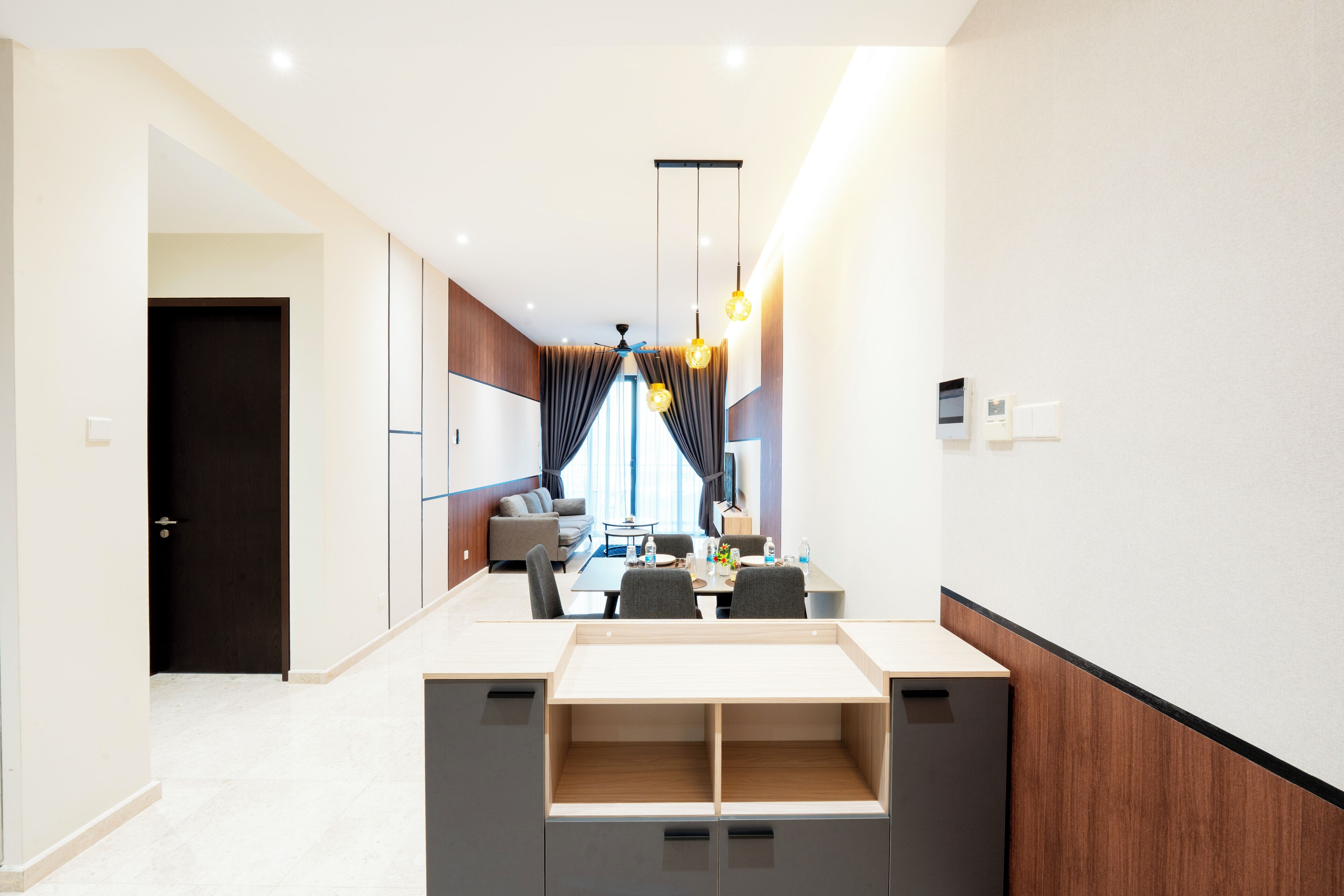 Una habitación de hotel moderna con zona de comedor, sofá y televisor.