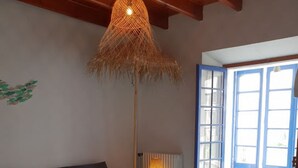 A cozy living room with a sofa, ottoman, and a hanging light fixture.