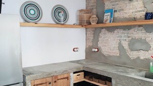 A kitchen with wooden cabinets, a stone countertop, and a brick wall.
