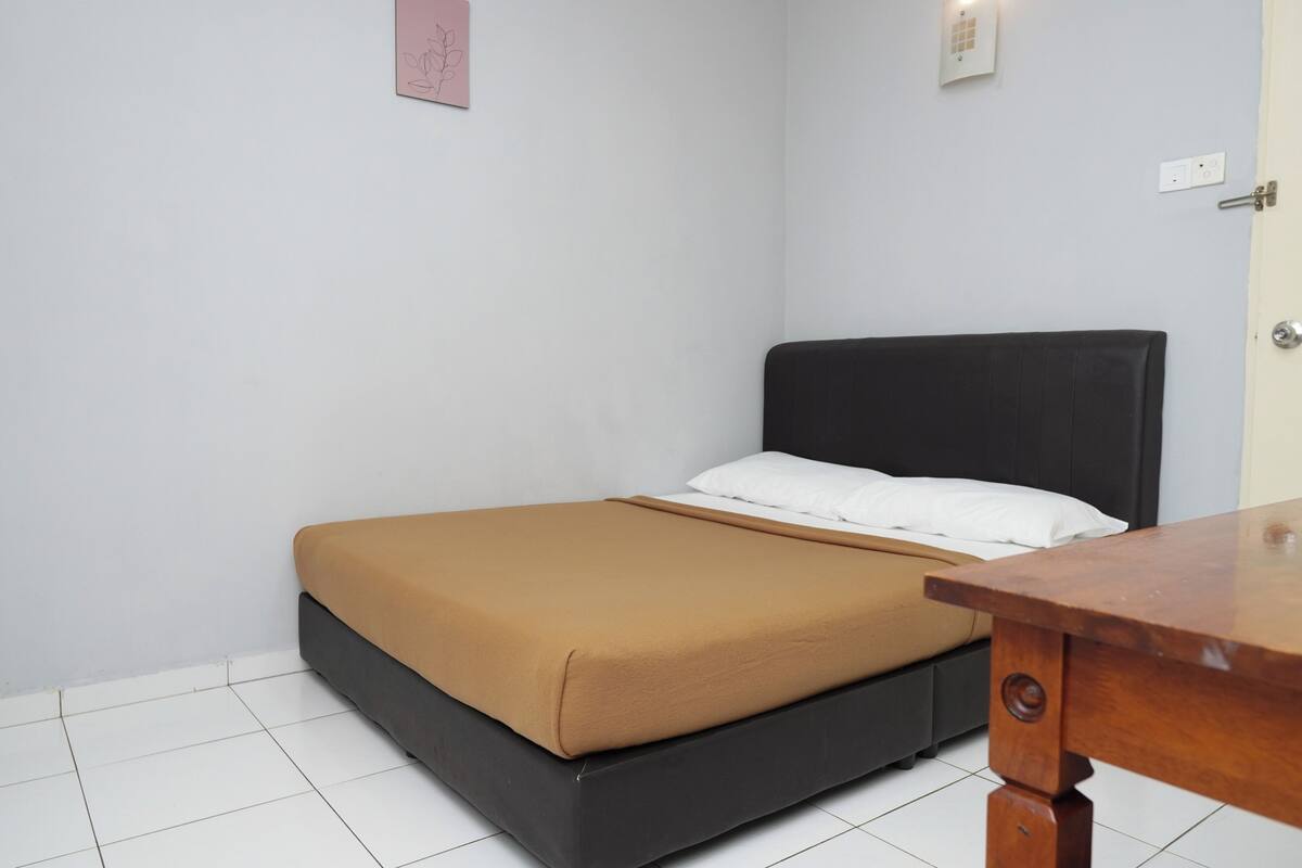 A bedroom with a bed, a wooden nightstand, and a door.