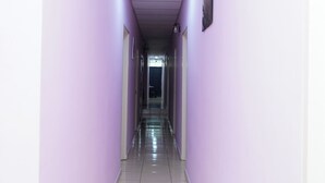 A long, narrow hallway with light purple walls and a tiled floor. - Hotel Sixty Nine (Johor Bahru)