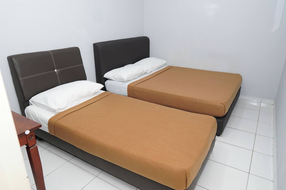A room with two beds, each with a headboard and a brown bedspread.
