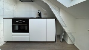 Une cuisine compacte dotée d’un four encastré, d’une machine à café et d’une lucarne au plafond.