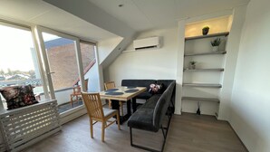 Un appartement moderne de style « loft », comprenant un coin repas, un canapé et un escalier menant à l’étage supérieur.