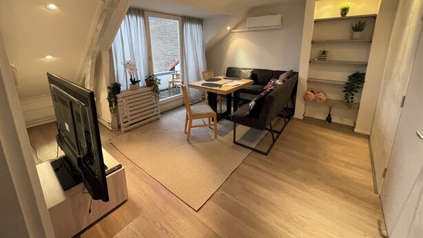 Un salon moderne comprenant un coin repas, un canapé, un téléviseur et un escalier menant à un niveau supérieur.
