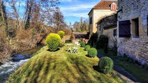 A stone house with a garden, a small stream, and a clear sky. - La Fermette au Banquet, Les Eyzies (Les Eyzies)