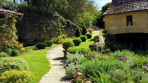 A stone pathway leading through a well-maintained garden with neatly trimmed hedges and a variety of plants. - La Fermette au Banquet, Les Eyzies (Les Eyzies)