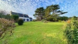 A house with a well-maintained lawn and a large tree in the front yard. - Seafront house with garden in Groix (Groix)