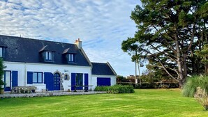 A two-story house with a well-maintained lawn and a large tree in the background. - Seafront house with garden in Groix (Groix)