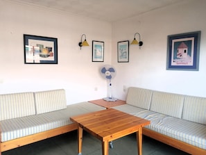 A room with two striped sofas, a wooden table, and wall-mounted lamps.