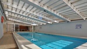 Una piscina interior amb terra de rajola, teulada coberta i un cartell que indica ús privat.