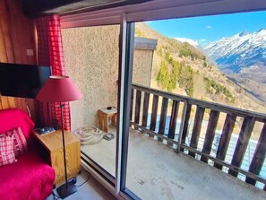 Una habitación con cama, lámpara, una mesita y vistas a las montañas.