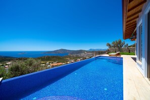 Ein klares, blaues Schwimmbecken mit Blick auf Meer und Berge.