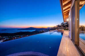 Ein moderner Infinity-Pool mit Blick auf den Ozean und einen Sonnenuntergang.
