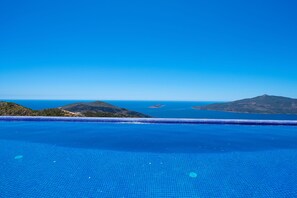 A clear view of a swimming pool with a tiled floor, surrounded by a mountainous landscape and the sea. - Akasya Ena in Kalkan Belediyesi (Kaş)