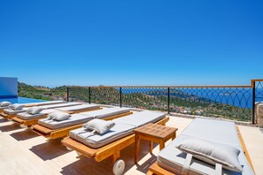 Eine Dachterrasse mit Liegestühlen und Blick auf das Meer.