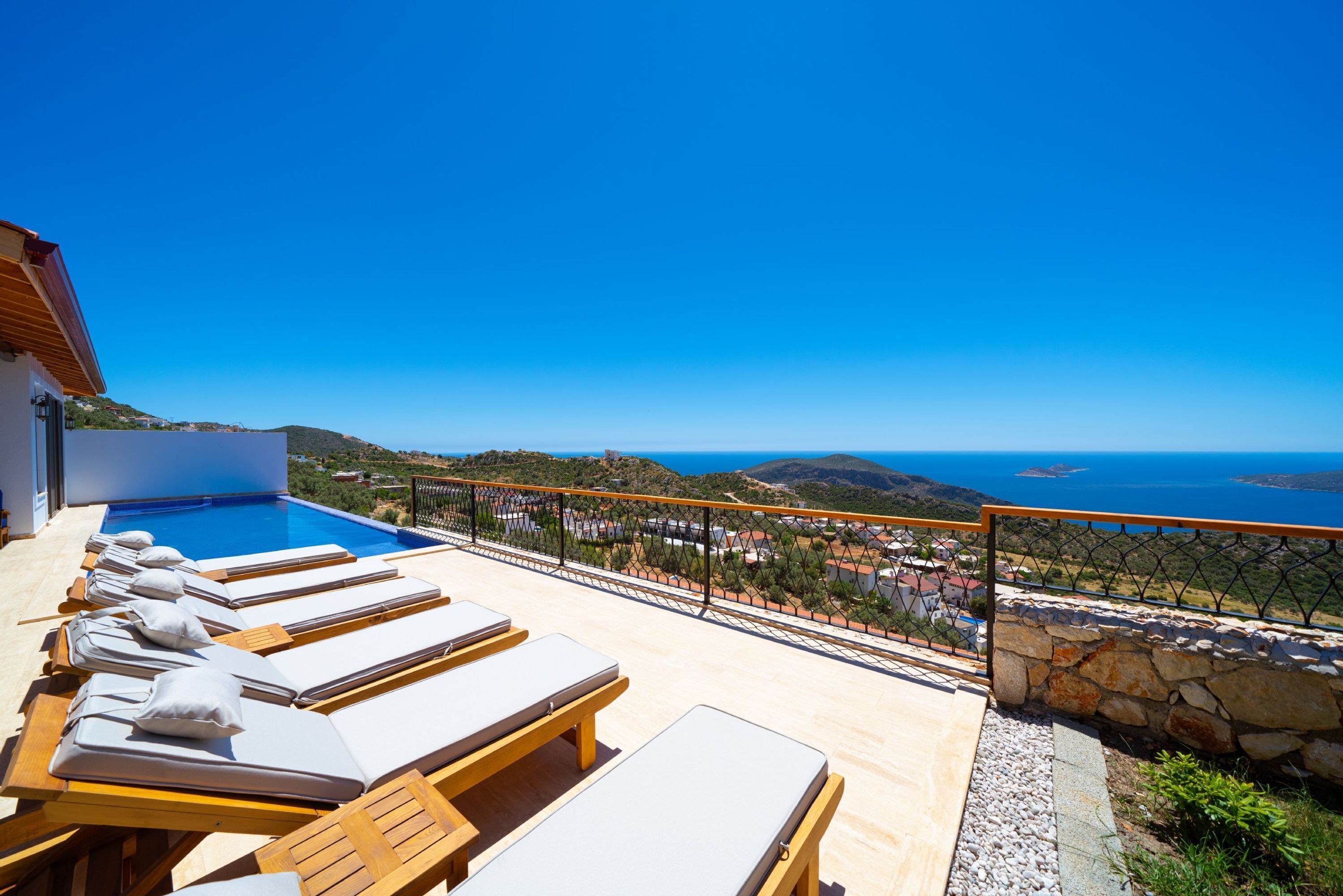 Ein Poolbereich mit Liegestühlen und Blick auf das Meer.