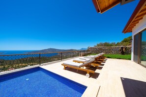 Ein Poolbereich mit Liegestühlen und Meerblick.
