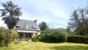 Ein Haus mit geneigtem Dach, einer Veranda und einem Rasen.