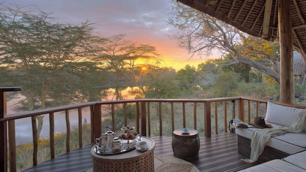 A deck with a sofa, a round table, and a small stool. - Finch Hattons (Tsavo)
