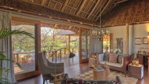 A spacious living area with a large window, a sofa, a chair, and a small table. - Finch Hattons (Tsavo)