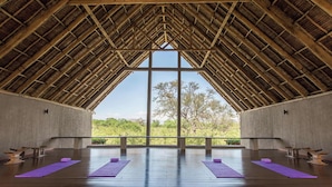 A spacious room with a high ceiling and large windows, wooden beams, and purple yoga mats on the floor. - Finch Hattons (Tsavo)