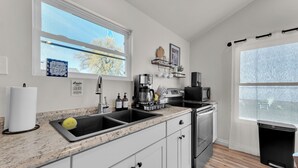 Una cocina moderna con un lavamanos doble, electrodomésticos de acero inoxidable y un amplio ventanal que proporciona luz natural.