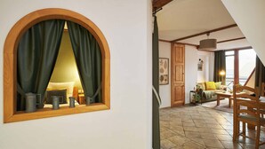 A room with a large arched mirror, a wooden chair, a small table, and a sofa with cushions. - Vincent Old Town Apartments  (Wroclaw)