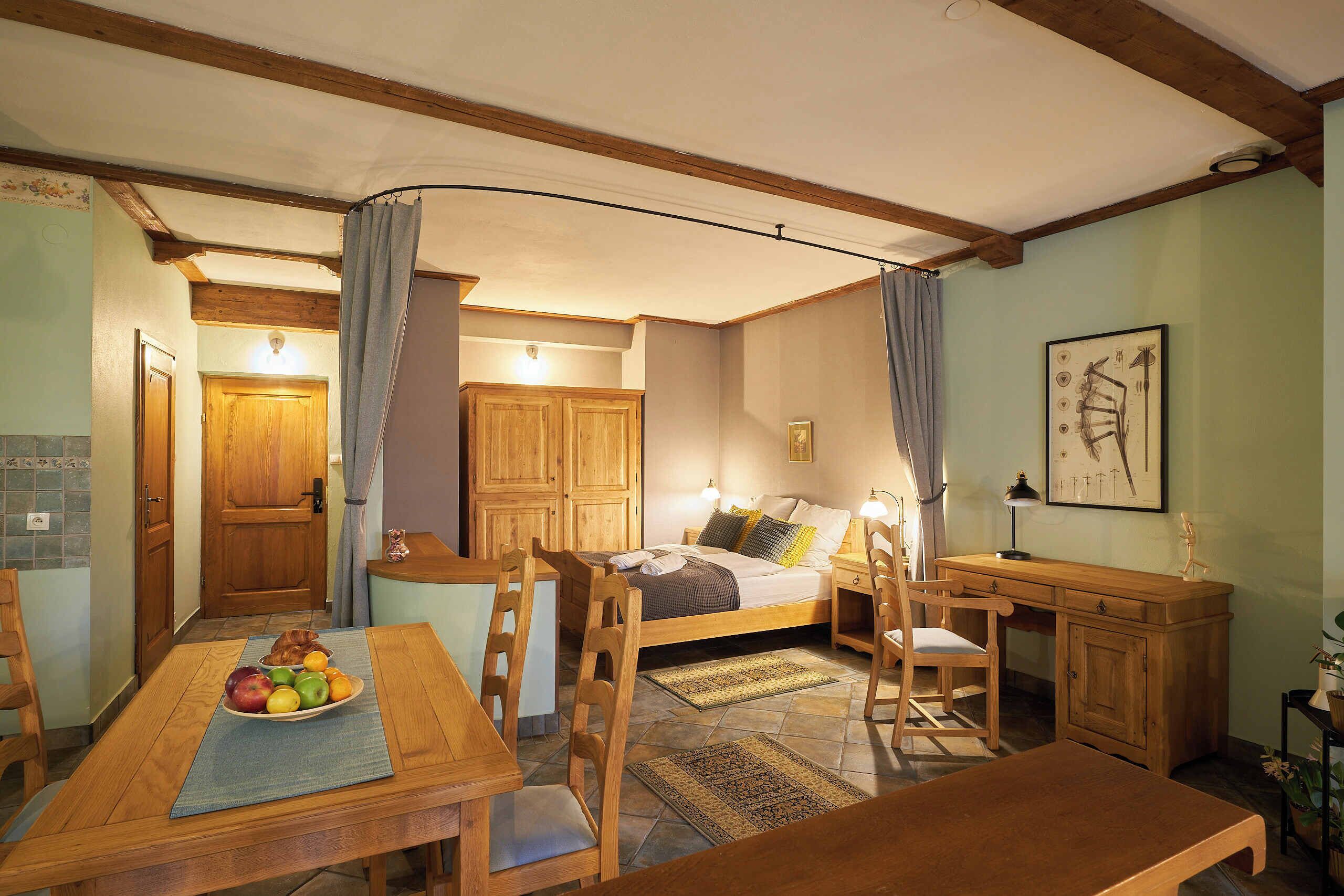 Una habitación acogedora con una cama, muebles de madera, una mesa de comedor con fruta y un escritorio.