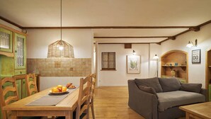 A cozy kitchen with wooden cabinets, a dining table with chairs, and a grey sofa. - Vincent Old Town Apartments  (Wroclaw)