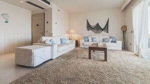 Una sala de estar moderna con un sofá blanco, una mesa de centro de madera y una alfombra grande.