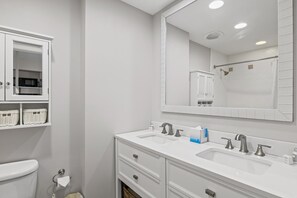 A modern bathroom with a white vanity, double sink, and a large mirror.