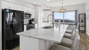Una cocina moderna con una isla grande, electrodomésticos de acero inoxidable y vistas a la ciudad.