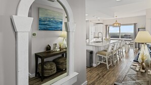 Cocina moderna con vistas, armarios blancos y una zona de comedor con sillas y una mesa.