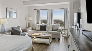 Una habitación de hotel moderna con una cama, un sofá, una mesita de centro y un televisor.
