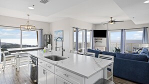 Una cocina moderna con una isla grande, armarios blancos y vistas al océano.