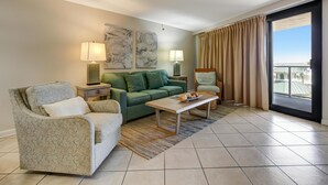 Ein modernes Wohnzimmer mit einem grünen Sofa, einem gemusterten Sessel, einem Holztisch und zwei Nachttischlampen.