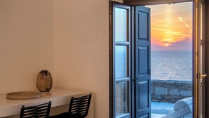 A room with a table and two chairs, a vase, and a view of the sea through an open door. - Ocean Villa - Res. I: Experience the Aegean Magnificence in style and privacy! (Paros)