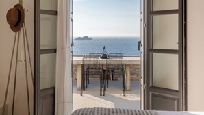 An open balcony with a table and chairs, a hat on a stand, and a view of the sea. - Ocean Villa - Res. I: Experience the Aegean Magnificence in style and privacy! (Paros)